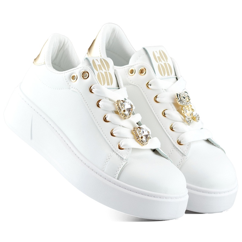 White fashionable women's sneakers with decorations on the laces, sneakers with a teddy bear
