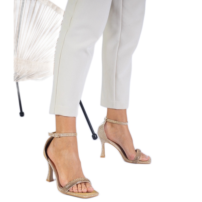 Golden elegant sandals on a high heel decorated with zircons