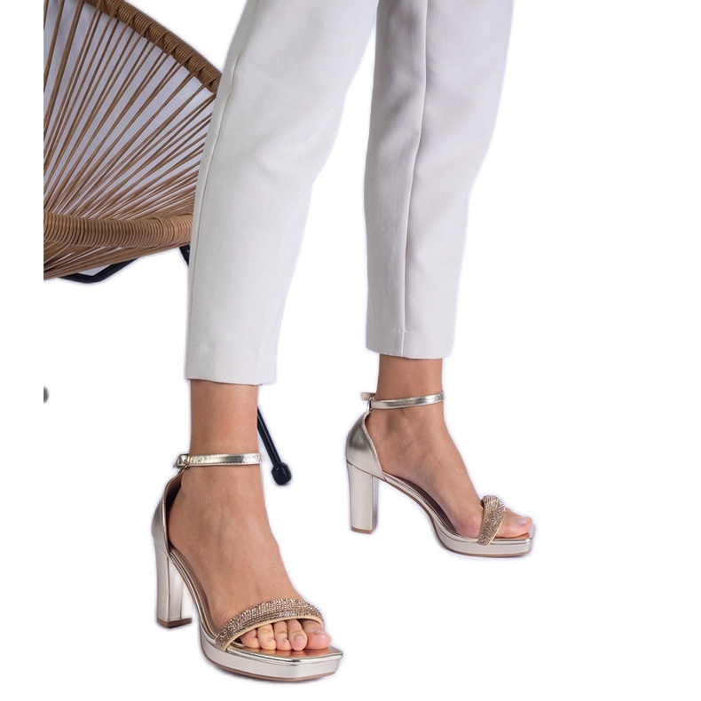 Golden elegant sandals on the pillar with zircons