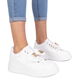 White sneakers decorated with a bow and a golden teddy bear