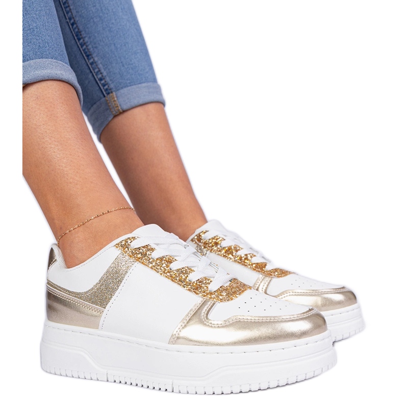 Golden women's sneakers on a thick sole decorated with glitter