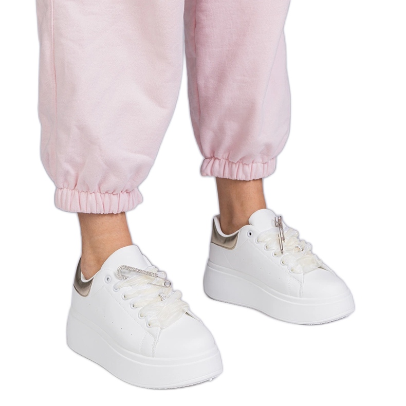 White sneakers with a golden insert and a zircon pin
