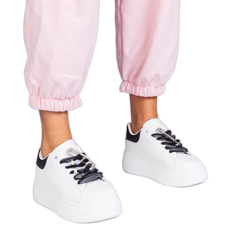 White sneakers with a black insert and a zircon pin