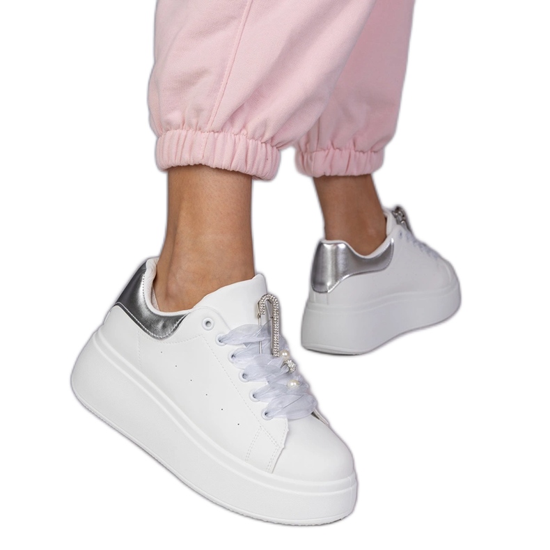 White sneakers with a silver insert and a pin with zircons
