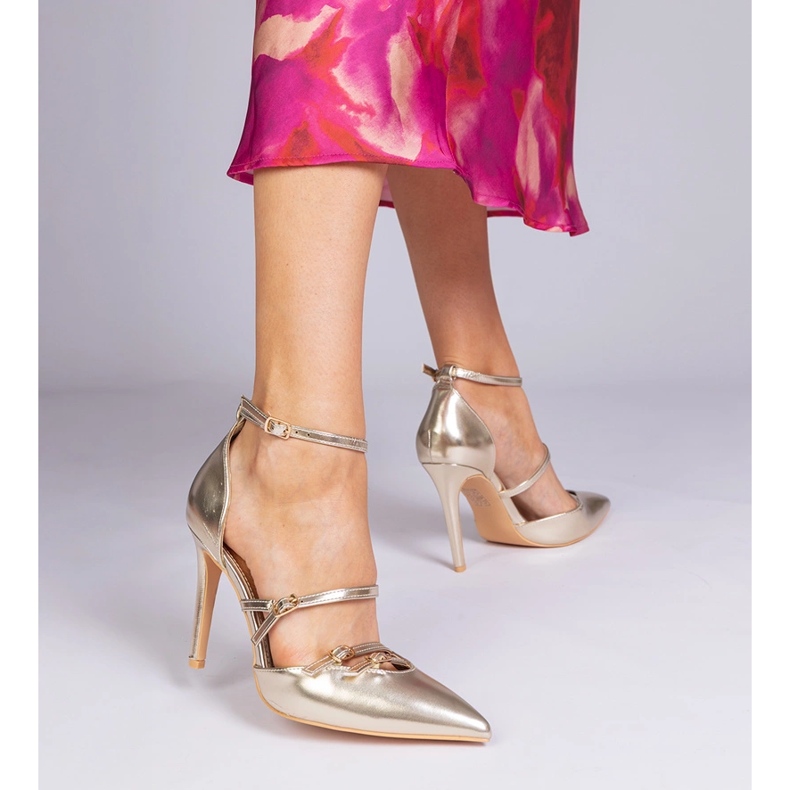 Golden pumps on a high heel fastened around the ankle 1